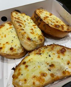 three pieces of bread with cheese on them in a box next to another piece of bread