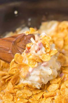 a wooden spoon scooping some food out of a crock pot filled with cereal