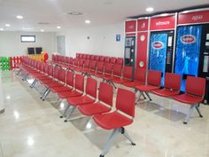 a row of red chairs sitting in front of vending machines at a game room