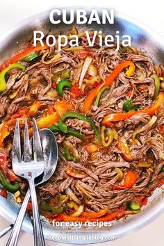 a close up of food in a pan on a table with a fork and spoon