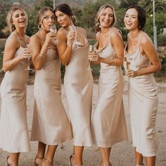 the bridesmaids are all dressed in champagne colored gowns and holding wine glasses