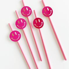 four pink straws with smiley faces on them