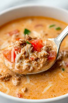 a spoon full of soup with meat and vegetables on it, ready to be eaten