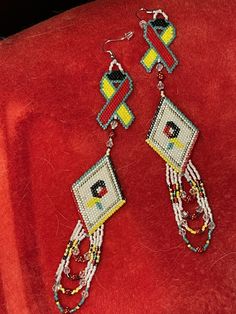 two pairs of beaded earrings sitting on top of a red cloth