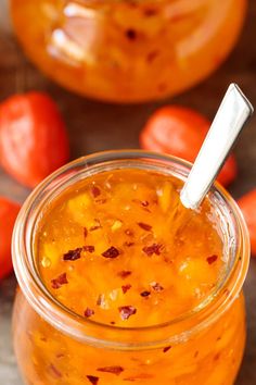 a glass jar filled with food sitting on top of a wooden table next to tomatoes