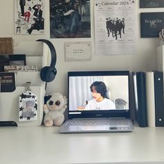 an open laptop computer sitting on top of a white desk next to a stuffed animal