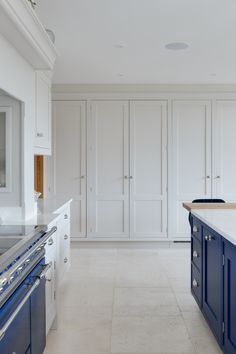 a large kitchen with white cabinets and blue appliances