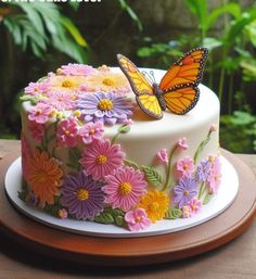 there is a cake with flowers and a butterfly on the frosting, sitting on a plate