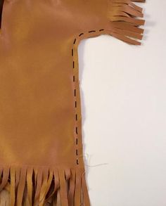 a brown leather purse with fringes on the side and stitching down the middle