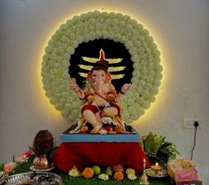 a statue of lord ganesh in front of a circular backdrop with flowers and candles