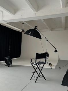 an empty photo studio with black curtains and lighting equipment on the floor in front of it