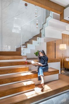 a woman sitting on the steps in a house with wood and glass railings above her