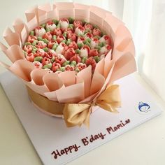 a birthday cake decorated with pink and green candies in a paper flower pot on top of a card that says happy bday minnie