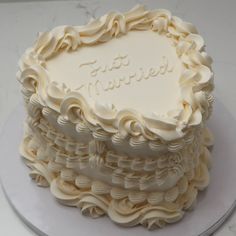 a wedding cake with white frosting on a marble counter top and the words, just married written in cursive writing