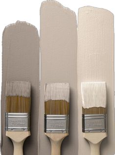 three paintbrushes are lined up against the wall, one is white and the other is beige