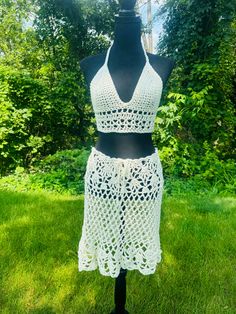 This outfit features a boho style halter top and lacy open weaved skirt. Perfect for festivals and rave parties. Made with 100% cotton yarn in ivory.  Wear to Coachella or a renfaire festival. Would makea great outfit for a beach wedding or party. Sweet 16 birthday gift or for summer vacation outfit.  Halter top ties in the back and around the neck. It fits A-C cups.  The long flowing breezy skirt ties around the waist for a loose or tighter fit. Comes down to right above knee or to knee length depending on height of person.  Measurements:  Skirt is 19 inches long and 34 inches around or can tighten with ties for a more snug fit.  Halter top fits A-C cups each cup is 6.5 inches long and wide. The band under the cups is 3.5 inches long. The neck and back ties are 18.5 inches long.  READY TO Beachwear Lace Crochet Top For Festival, Hippie Triangle Halter Top For Festivals, Festival Lace Crochet Top Beachwear, Festival Beachwear Crochet Lace Top, Festival Lace Crochet Top For Beachwear, Bohemian Fitted Swimwear For Beach Party, Bohemian Fitted Swimwear For Festival, Fitted Bohemian Swimwear For Beach Party, Bohemian White Triangle Top Swimwear