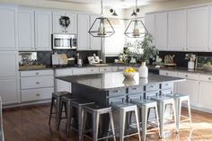 a kitchen island with four stools in front of it and a bowl of fruit on the counter