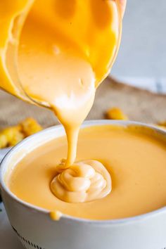 a person pouring sauce into a white bowl filled with corn kernels on the side