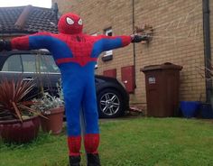 a man in a spiderman costume standing on the grass with his arms outstretched and hands out