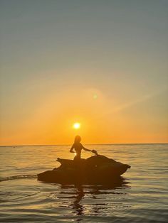 a person on a jet ski in the ocean at sunset