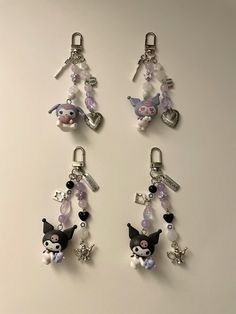 four key chains with charms attached to them on a white surface in front of a wall