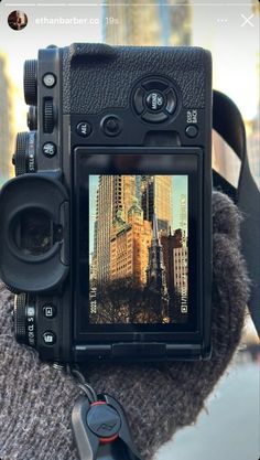 a camera is sitting on top of a person's arm with the city in the background