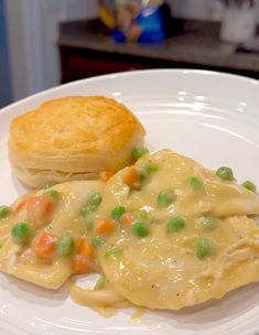 a white plate topped with chicken pot pie and biscuits