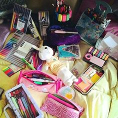 the contents of a purse are laid out on a bed, including pens, markers and pencils