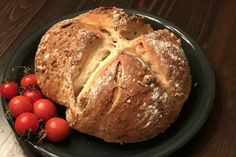 a black plate topped with a loaf of bread and cherry tomatoes