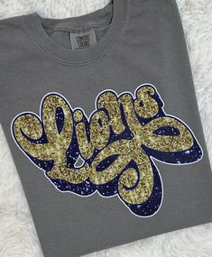 Gold & navy faux sequin Lions shirts.   Comfort Colors brand unisex short sleeve shirts. Sizes adult small-2xl are available. Ivory, white, or gray available in adult sizes.  Comfort Colors brand youth shirts in sizes xs-xl. Youth are only available in short sleeve tees. White and gray are the colors available in youth. Please choose the shirt size from the drop down box.   In the case that my distributors are out of stock on a certain size/color, I will message you on Etsy to arrange a refund or change in order. Please download the Etsy app so you can receive messages. In the case that you do not respond, the order will be canceled because I do not have access to your contact info. Thank you for understanding. Each item ordered from my shop is custom made. No two items will be identical. Spirit Wear Shirts, Back To School Shirts, School Spirit Wear, School Spirit Shirts, Lion Shirt, Spirit Shirts, Vinyl Shirts, Comfort Colors Shirt, Spirit Wear