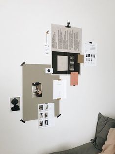 a white wall with several pieces of paper on it and pictures hanging from the wall