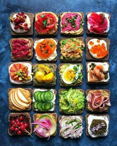 several different types of food are arranged in squares on a blue table top, including breads and vegetables