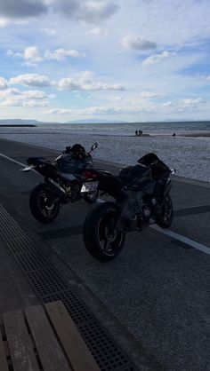 two motorcycles parked next to each other on the side of a road near the ocean