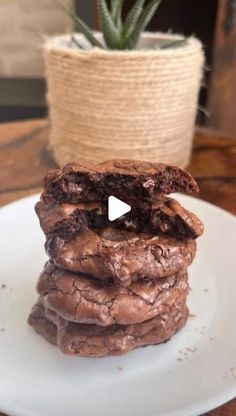 a stack of cookies sitting on top of a white plate next to a potted plant