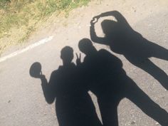 two people standing next to each other with their shadow on the ground and one person holding a basketball