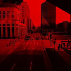 a red and black photo of a city street with tall buildings in the back ground