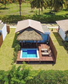 an aerial view of a house with a swimming pool in the yard and thatched roof