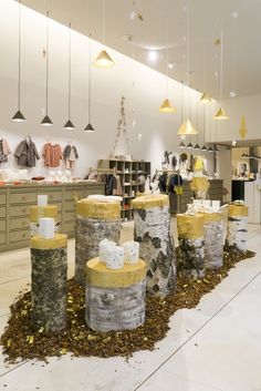 the interior of a clothing store with several wooden barrels in front of it and lights hanging from the ceiling