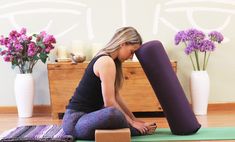 a woman is sitting on the floor with a yoga mat