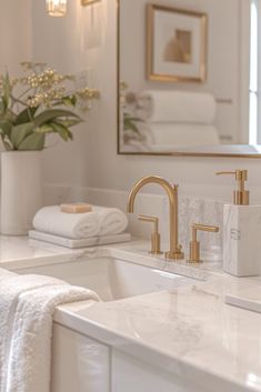 a white bathroom with gold faucets and marble counter tops, along with towels