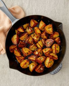 a pan filled with cooked potatoes on top of a table next to a cloth and spoon