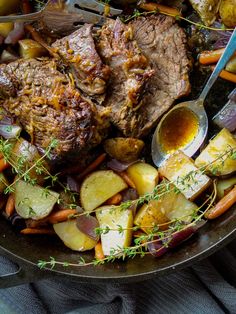 a pan filled with meat, potatoes and carrots