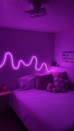 a bed in a room with purple lights on the wall and pillows sitting next to it