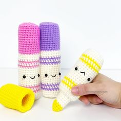 three crocheted objects with faces on them are being held by a person's hand