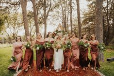 a group of women standing next to each other on top of a rug in front of trees