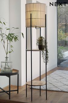 a floor lamp with a plant on it in a living room next to a rug