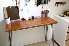 a wooden table topped with lots of crafting supplies next to a white washer and dryer