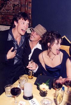 three people sitting at a table with wine glasses