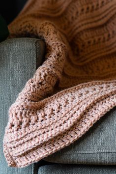 a knitted blanket sitting on top of a couch