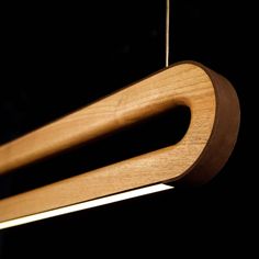 a wooden object hanging from a string on a black background with light coming through it